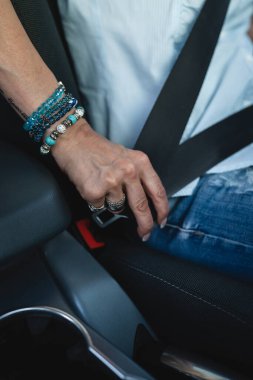 One woman caucasian female driver sitting in the car fastening seat belt holding with hand driving safety concept copy space selective focus on hands