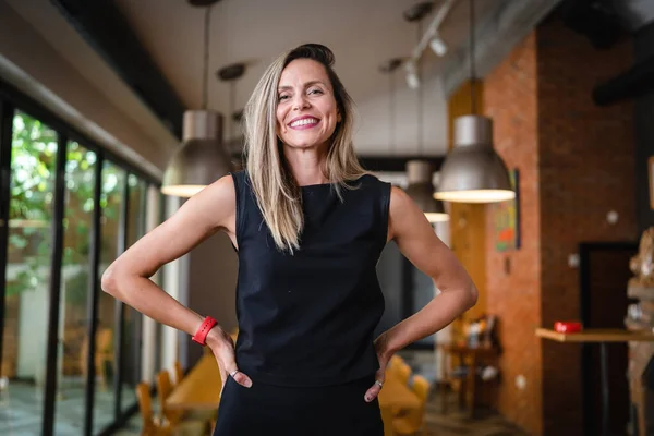 One woman middle age caucasian female standing at home in dining room or restaurant happy smile confident wear black waist up copy space front view portrait