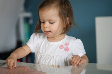 One girl small caucasian toddler child eat bread at home copy space wear white dress looking curious alone growing up childhood development concept