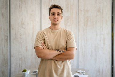 One man adult caucasian male standing in front of table desk at work in the office or work from home wear shirt looking confident casual serious copy space real people freelance work