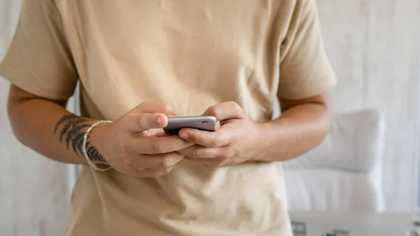 Close up on hands of unknown caucasian man standing in the office or at home in day using mobile phone to make a call or send sms text message or browse internet social network