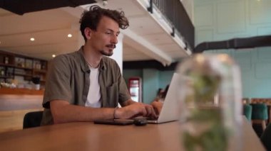 One adult modern man caucasian male with beard and mustaches wear causal shirt working remote from cafe freelance work or blog checking online content or browsing internet while sitting alone