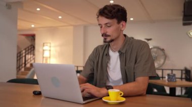 One adult modern man caucasian male with beard and mustaches wear causal shirt working remote from cafe freelance work or blog checking online content or browsing internet while sitting alone