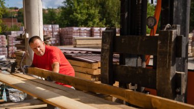 One man caucasian adult male standing at warehouse checking wooden plank choosing lumber at fork lifter for construction material copy space