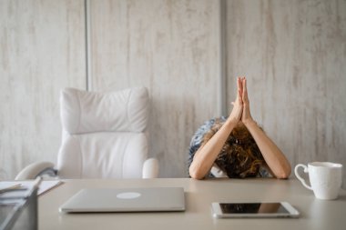 Serbest çalışan bir kadın dizüstü bilgisayarla masa başında otururken esniyor. Boyun ağrısı, aşırı çalışma ve yorgunluk yüzünden sırtı ağrıyor.