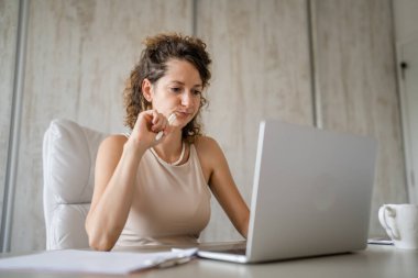 Genç bir beyaz kadın, beyaz kadın girişimci ya da iş kadını. Küçük işletme yöneticisi, ofisteki dizüstü bilgisayarında çalışıyor. Parlak bir fotokopi alanında.