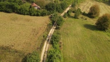 Yukarıdan insansız hava aracı videosu, kırsal kesimde kırsal kesimde bisikletle bisiklet süren bir grup insanı takip ediyor. Yazın toprak yolda ve tarlada eğlence amaçlı eğlence amaçlı aktivite kavramı doğada.
