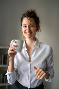 Bir iş kadını genç yetişkin kadın Kafkasyalı sabah ofiste duruyor. Kendine güler yüzlü, bir fincan kahve fotokopisi alan.