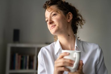 Bir iş kadını genç yetişkin kadın, sabah ofiste duruyor. Bir fincan kahve ve fotokopi alanı ile kendinden emin.