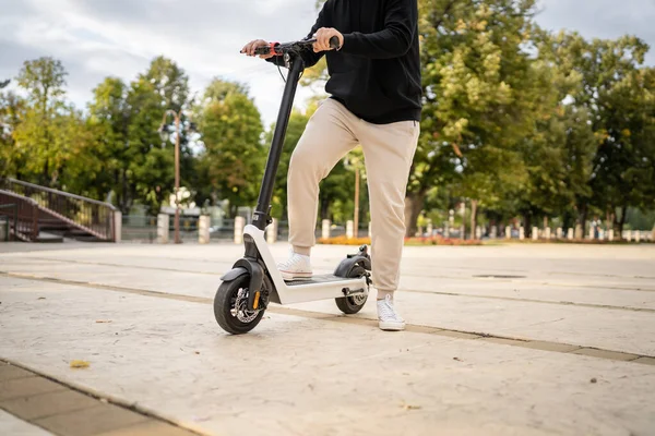 昼間の舗装上の電動キックスクーター電子スクーターを立っているか または運転未知の男の足環境に優しい近代的な輸送 — ストック写真