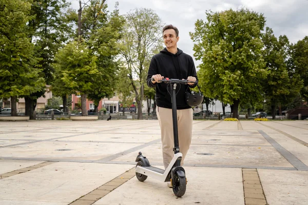 1人の若者成人白人男性電動キックスクーターに乗って町や市内を走行します電子スクーター輸送の環境に優しいモード実際の人々は完全な長さのスペースをコピーします — ストック写真