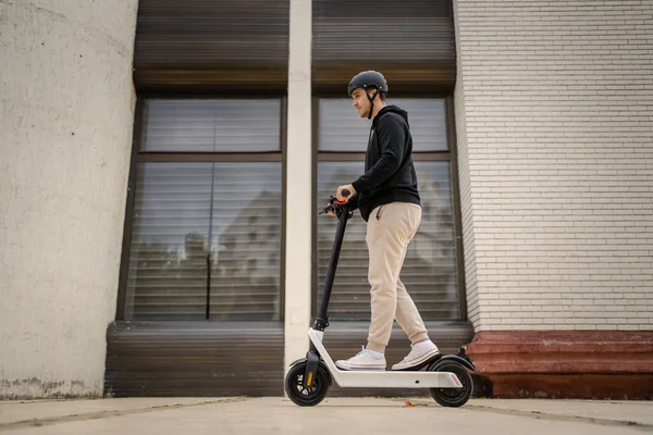 1人の若者成人白人男性電動キックスクーターに乗って町や市内を走行します電子スクーター輸送の環境に優しいモード実際の人々は完全な長さのスペースをコピーします — ストック写真