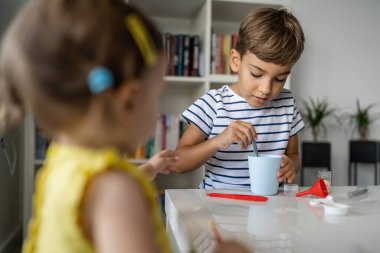 Evde oyuncaklarla oynayan iki çocuk. Bir erkek anaokulu öğrencisi. Küçük kız kardeşiyle birlikte çocukluk deneyleri yapıyor.