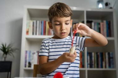 Anaokulundan bir çocuk bilim deneyi oyuncaklarıyla masada oturuyor. Kameraya bakıyor. Gülümseyen çocukluk dönemi konsepti.