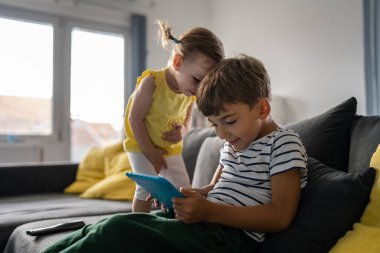 erkek ve kız kardeş küçük beyaz çocuk evde video oyunu oynamak için dijital tablet kullanıyor.