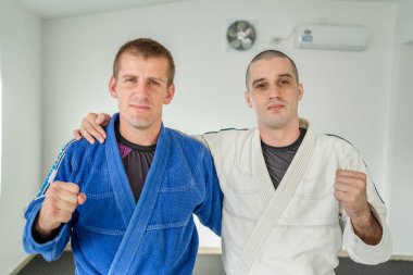 İki Brezilyalı jiu jitsu bjj atleti spor salonunda portre önünde siyah kuşak dövüş sanatları pratisyeni kimono gi üniforması giyiyor.