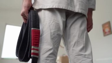 Beyaz kimonolu beyaz bir sporcunun elinde siyah bjj kuşağı Brezilya jiu jitsu dövüş sanatları eğitimi kavramını tutarken 