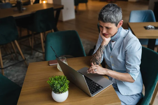 ラップトップコンピュータで働くテーブルカフェに座っている1人の女性成熟した大人の白人シニア女性リモートオンライン現実の人々コピースペース現代的なライフスタイルコンセプト自信のある女性ビジネス起業家 — ストック写真