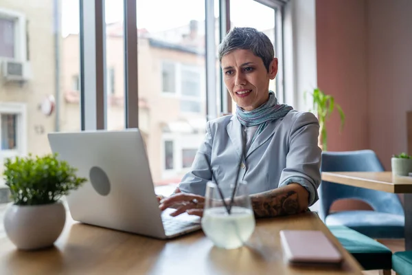 ラップトップコンピュータで働くテーブルカフェに座っている1人の女性成熟した大人の白人シニア女性リモートオンライン現実の人々コピースペース現代的なライフスタイルコンセプト自信のある女性ビジネス起業家 — ストック写真