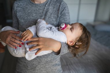 Küçük beyaz bir kız çocuğu bilinmeyen annesinin ellerinde uyuyor. Kızı evde uyuyordu. Çocukluk bakımında ve büyüme konseptinde.