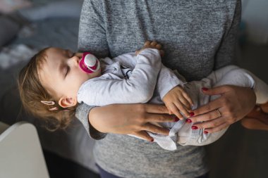 Küçük beyaz bir kız çocuğu bilinmeyen annesinin ellerinde uyuyor. Kızı evde uyuyordu. Çocukluk bakımında ve büyüme konseptinde.