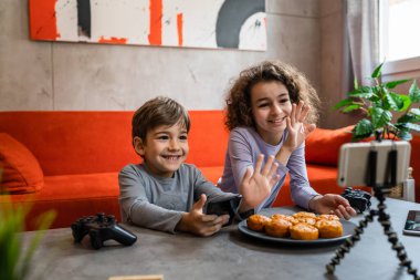 Erkek ve kız kardeş iki kardeş cep telefonuyla video blogu yapıyorlar evlerinden internet günlüğü için en sevdikleri oyuncak eleştirisi hakkında sosyal ağ kopyalama alanı için içerik oluştur ve paylaş