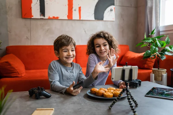 Erkek ve kız kardeş iki kardeş cep telefonuyla video blogu yapıyorlar evlerinden internet günlüğü için en sevdikleri oyuncak eleştirisi hakkında sosyal ağ kopyalama alanı için içerik oluştur ve paylaş