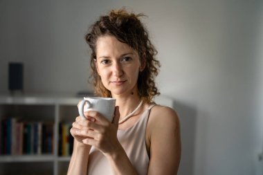 Bir kadın Kafkas girişimci iş kadını ya da sekreteri iş yerinde durmuş bir fincan kahve içiyor ve bir fotokopi çekiyor.