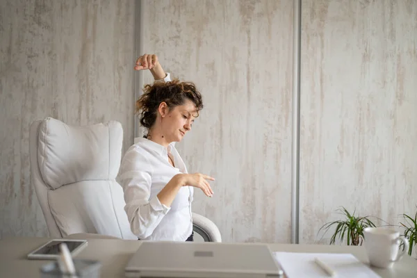 One woman freelancer stretch in the office at work sitting in chair at desk using laptop computer having pain sore back suffering from neck ache overwork and exhaustion concept copy space