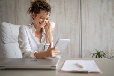 Genç bir iş kadını Kafkasyalı kadın dijital tablet kullanarak ofise geri dönüyor ve kahve girişimcisi modern iş konseptini içiyor.