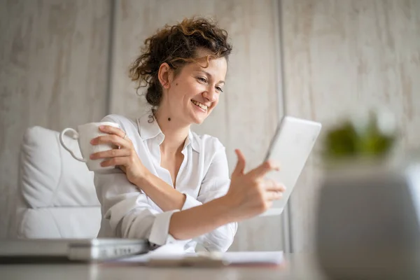 One young business woman caucasian female back to the office talking online using digital tablet while working and drinking coffee entrepreneur modern business concept