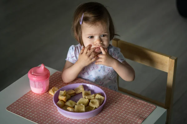 一人で家のテーブルに座っている一人の女の子の小さな白人の子供は 一日で一人でヨーグルトと朝食やランチの食事のペストリーを食べます現実の人々は 開発の概念コピースペースを成長 — ストック写真
