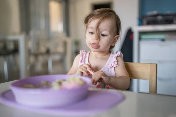 1人の子供小さな白人の幼児女性の赤ん坊はテーブルで一人で家で食べる現実の人々はスペースをコピーします — ストック写真