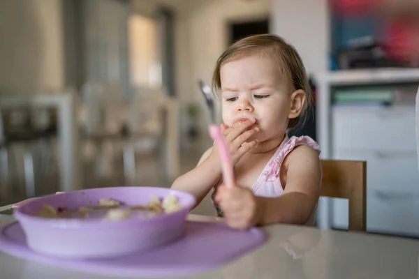 1人の子供小さな白人の幼児女性の赤ちゃんは 部屋の自宅で一人でテーブルで食べるスプーンを保持します — ストック写真