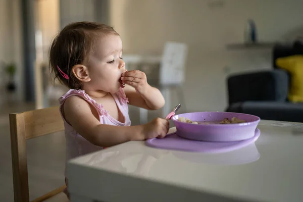 1人の子供小さな白人の幼児女性の赤ん坊はテーブルで一人で家で食べる現実の人々はスペースをコピーします — ストック写真