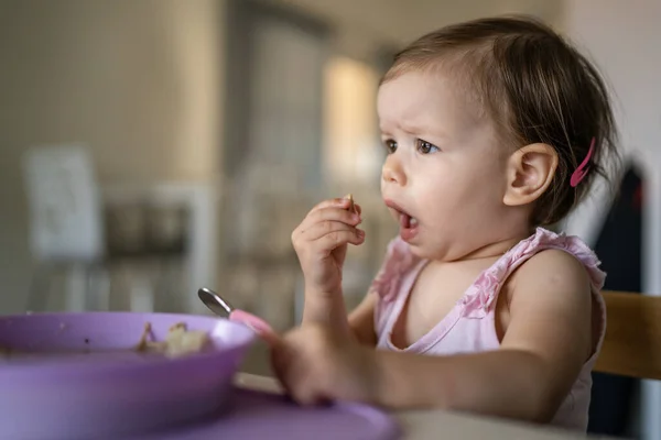 1人の子供小さな白人の幼児女性の赤ん坊はテーブルで一人で家で食べる現実の人々はスペースをコピーします — ストック写真