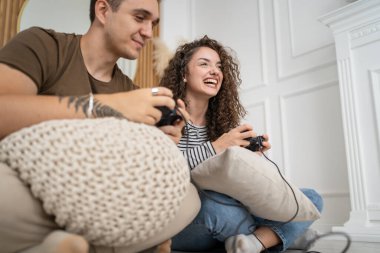 İki kişi, çift erkek ve kadın sevgili karı koca ya da arkadaşlar oyun oynuyorlar oyun kumandası tutuyorlar mutlu gülüşler, duygusal jest tepkileri, aile içi boşlukları dolduruyorlar.