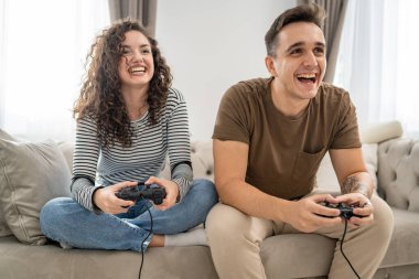 İki kişi, çift erkek ve kadın sevgili karı koca ya da arkadaşlar oyun oynuyorlar oyun kumandası tutuyorlar mutlu gülüşler, duygusal jest tepkileri, aile içi boşlukları dolduruyorlar.