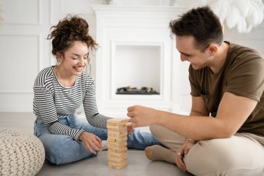 Kadın ve erkek mutlu beyaz çift ya da evde Jenga masası oyunu oynayan arkadaşlar mutlu bir gülücük keyfi birlikte vakit geçiriyorlar aile zamanlarını kopyalayan gerçek insanlar.