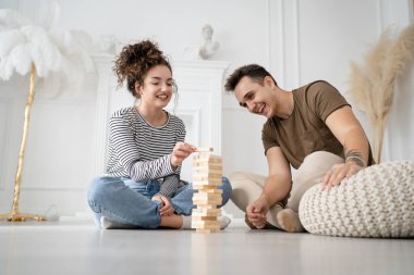 Kadın ve erkek mutlu beyaz çift ya da evde Jenga masası oyunu oynayan arkadaşlar mutlu bir gülücük keyfi birlikte vakit geçiriyorlar aile zamanlarını kopyalayan gerçek insanlar.