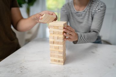 Jenga oyunu için tuğla istifleyen beyaz bir kadının elini kapatıyoruz. Tahta parçaları kuleyi kapatıyor. Uzay ailesinin oyun tahtasını kopyalıyor.