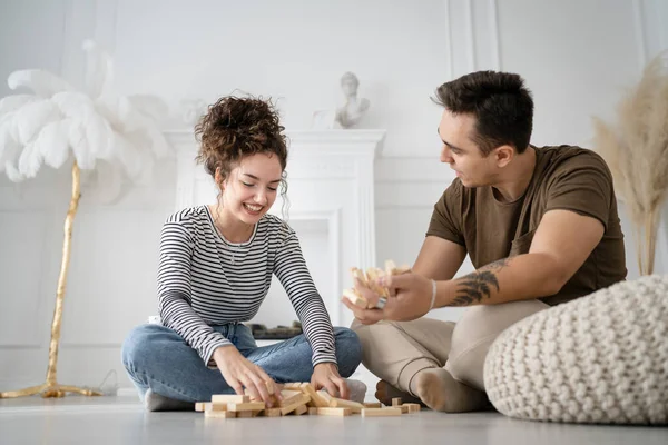 女人和男人快乐的高加索夫妇丈夫和妻子或朋友在家里玩Jenga桌上游戏快乐的微笑闲暇的呆在一起家庭时间复制空间真实的人 — 图库照片
