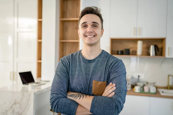 一位年轻的白种人男子日前站在厨房里的正面画像 开心地微笑着 自信地模仿空间腰部的真人 — 图库照片