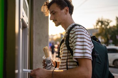Bir adam genç yetişkin modern milenyum turisti ATM makinesiyle para çekmek için şehir yaşamını modern yaşam konseptini kullanıyor.