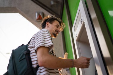 Bir adam genç yetişkin modern milenyum turisti ATM makinesiyle para çekmek için şehir yaşamını modern yaşam konseptini kullanıyor.