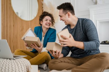 Genç çift erkek ve kadın erkek ve kız arkadaş ya da karı koca hediyelerini evde değiştirip birbirlerine hediye veriyorlar ve mutlu bir gülümseme açıyorlar sevgililer günü bayramı ya da doğum günü kutluyorlar.
