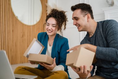 Genç çift erkek ve kadın erkek ve kız arkadaş ya da karı koca hediyelerini evde değiştirip birbirlerine hediye veriyorlar ve mutlu bir gülümseme açıyorlar sevgililer günü bayramı ya da doğum günü kutluyorlar.