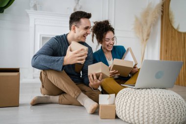 Kafkasyalı genç bir çift, karı-koca, karı-koca ya da sevgili evde bilgisayarın önünde hediye kutusunu açıp internetten fotokopi çekiyorlar.