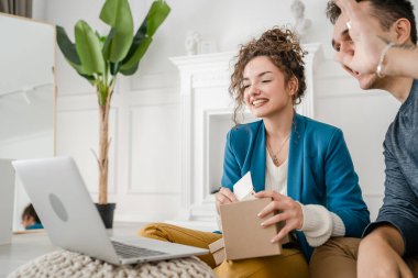 Kafkasyalı genç bir çift, karı-koca, karı-koca ya da sevgili evde bilgisayarın önünde hediye kutusunu açıp internetten fotokopi çekiyorlar.