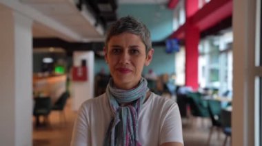 Kafkasya 'da, evde ya da kafeteryada kameraya bakıp gülümseyen, kendine güvenen, beyaz gömlek ve eşarp giyen, modern, yetişkin bir kadının portresi.